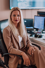 Image showing A businesswoman sitting in a programmer's office surrounded by computers, showing her expertise and dedication to technology.