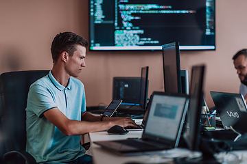 Image showing A programmer diligently testing smartphone applications while sitting in their office.