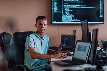 Image showing A programmer diligently testing smartphone applications while sitting in their office.