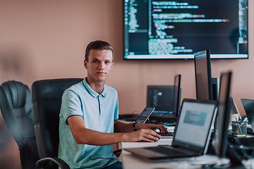 Image showing A programmer diligently testing smartphone applications while sitting in their office.