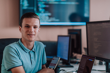 Image showing A programmer diligently testing smartphone applications while sitting in their office.