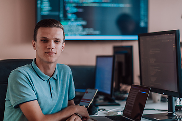 Image showing A programmer diligently testing smartphone applications while sitting in their office.