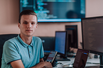 Image showing A programmer diligently testing smartphone applications while sitting in their office.