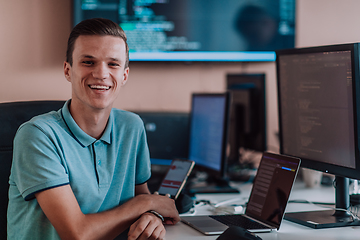 Image showing A programmer diligently testing smartphone applications while sitting in their office.