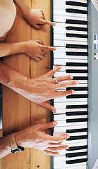 Image showing Piano, top view and hands of kid learning with father in home, playing or bonding together. Development, education or parent teaching child how to play music instrument, acoustic or electric keyboard