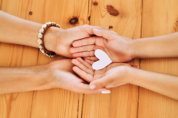 Image showing Hands holding, heart and shape of love by parent and child in support, care and unity together on a table in a home. Top view, family and people in adoption with hope symbol and bonding