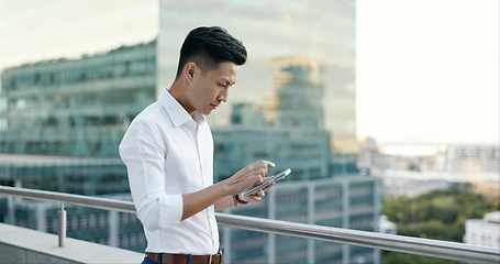 Image showing Asian man, city business and phone on rooftop of office building for social networking, mobile app search and reading economy news notification. Worker, balcony and typing on smartphone technology