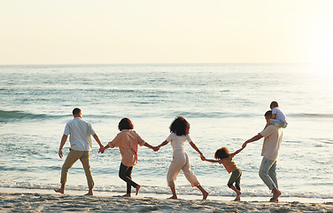 Image showing Walking, big family and holding hands at beach at sunset, having fun and bonding on vacation outdoors. Care, mockup and kids, grandmother and grandfather with parents at ocean enjoying holiday time.