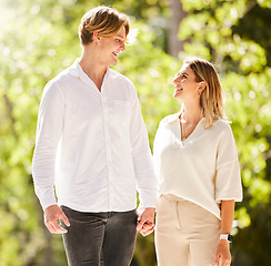 Image showing Couple, walking and smile in park, garden and nature for partner love, romantic care or happiness together. Happy man, young woman and walk outdoor in sunshine, summer date or relax on valentines day