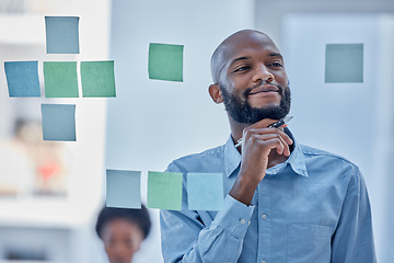 Image showing Black man, writing and thinking in planning schedule on glass board for brainstorming tasks at office. African male wondering in thought for project plan, idea or sticky note for company strategy