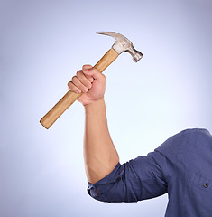 Image showing Hammer, construction worker tool and hand in a isolated, blue background and studio. Handyman, house building and maintenance contractor career with man hands holding a builder and repair tools