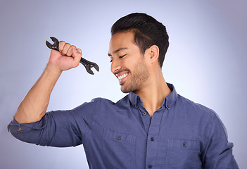 Image showing Man, studio and happy with tools or spanner for handyman, maintenance or repair work. Smile of Asian model person flex strong muscle on purple background for engineer, mechanic or technician job