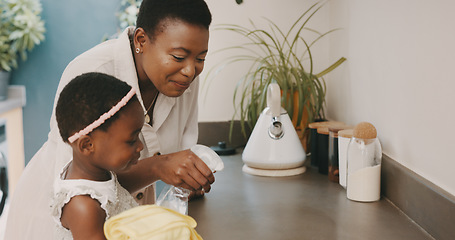 Image showing Little girl helping her mother with household chores at home. Happy mom and daughter wearing gloves while spraying and scrubbing the kitchen counter together. Kid learning to be responsible by doing