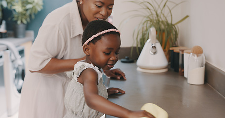 Image showing Little girl helping her mother with household chores at home. Happy mom and daughter wearing gloves while spraying and scrubbing the kitchen counter together. Kid learning to be responsible by doing