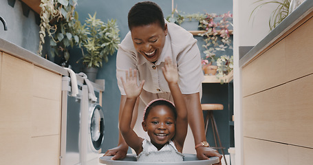 Image showing Playful black mother pushing her daughter around in a laundry basket at home. Young woman and her child playing and having fun while spending time at home