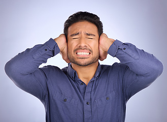 Image showing Stress, noise and man closing his ears in studio isolated on a gray background. Loud, mental health and upset, angry or mad business person with headache, depression or anxiety from noisy sound.