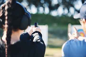 Image showing Woman, gun and learning to shoot outdoor with instructor at shooting range for target training. Safety and security with hand teaching person sport game or aim with gear and firearm for focus