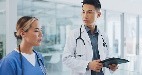 Image showing Healthcare, nurse and doctor talking, walking in lobby and consultation for advice, diagnosis and tablet. Medical professionals, Asian man and woman in hospital, update charts or planning for surgery