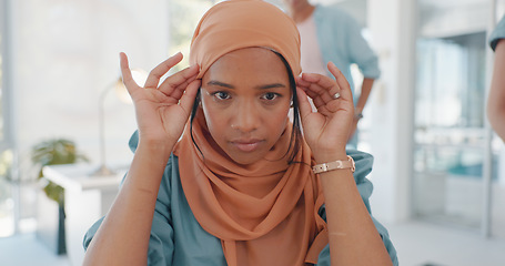 Image showing Face, muslim and working with a business woman adjusting her hijab while sitting in the office for work. Hands, head or empowerment with an islamic female employee moving her headscarf in a workplace