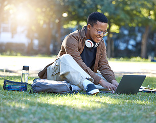 Image showing Black man, park studying and laptop work in a campus garden with a smile and lens flare, Outdoor, happiness and online elearning with a textbook of a student busy with exam study on university grass