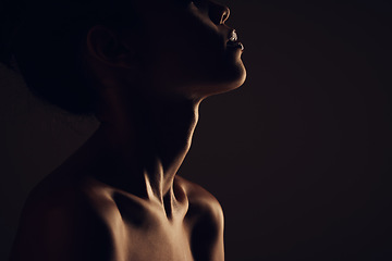 Image showing Beauty, woman and silhouette dark background of skin, body and model with glow, light and art on black. Face of aesthetic model person in studio for abstract, creativity and shadow profile or space