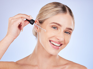 Image showing Face, portrait and skincare of woman with serum in studio isolated on a blue background. Dermatology, beauty cosmetics and happy female model apply hyaluronic acid, retinol or essential oil product.