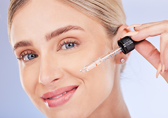 Image showing Portrait, face and skincare of woman with serum in studio isolated on a blue background. Dermatology cosmetics, beauty closeup and happy female model apply hyaluronic acid, retinol or essential oil.