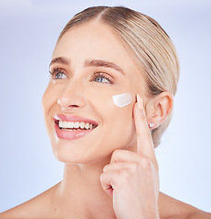 Image showing Face, beauty skincare and woman with cream in studio isolated on a blue background. Dermatology cosmetics, thinking and happy female model apply lotion, creme or moisturizer product for healthy skin.