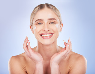 Image showing Portrait, face skincare and woman with cream in studio isolated on a blue background. Dermatology cosmetics, beauty and happy female model apply lotion, creme or moisturizer product for healthy skin.