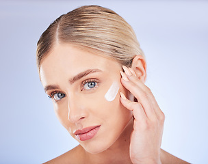 Image showing Face portrait, skincare and woman with cream in studio isolated on a blue background. Facial dermatology, beauty cosmetics and young female model apply hydration lotion, creme or moisturizer product