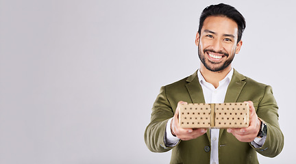 Image showing Gift, box and portrait of a man in a studio for a celebration or birthday or event with mockup space. Present, happy and male model from Mexico giving a souvenir with happiness by a gray background.