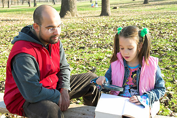 Image showing child and father reading the book