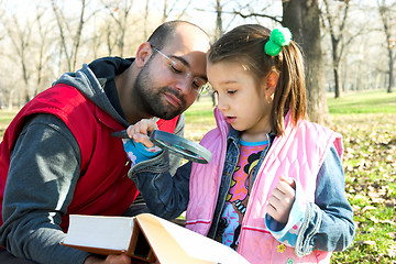 Image showing child and father reading the book