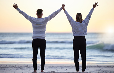 Image showing Couple at beach with hands up, freedom and travel, ocean waves and view, love and adventure together. Relationship, carefree and peace with man and woman with arms in air, back and sunrise in Bali