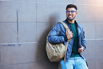 Image showing Happy, laughing and man on a wall for education, studying and university in the city. Smile, looking and student ready to start college on a campus for learning, scholarship and excited about school