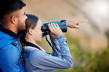 Image showing Binoculars, pointing and a couple bird watching in nature while hiking in the mountains together. Forest, nature or sightseeing with a man and woman looking at the view while bonding on a hike