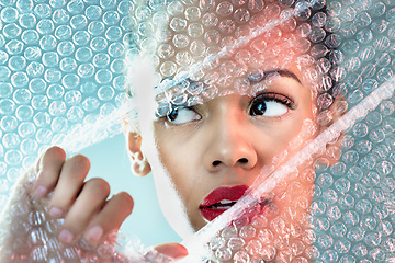 Image showing Bubble wrap, beauty and face of woman with makeup, cosmetics and skincare products in studio. Creative art deco, salon aesthetic and thinking girl with glow, lipstick and luxury style with plastic