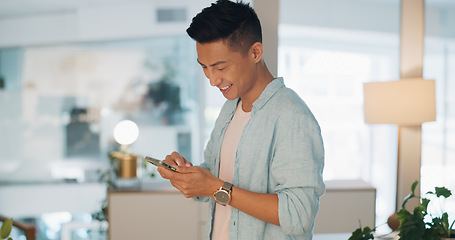 Image showing Cellphone, networking and Asian man on social media in the office typing on a lunch break. Technology, happy and male employee with a smile browsing internet or mobile app with cellphone in workplace