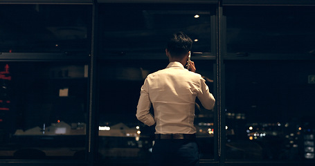 Image showing Business man, phone call and window at night in modern office building for global networking or negotiation. Finance, talk strategy rear and corporate worker using phone, communication and city bokeh