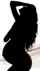 Image showing Beauty, body and silhouette of a pregnant woman in a studio with chiffon material, fabric or textile. Art, pregnancy and shadow figure of a beautiful maternal female model posing by white background