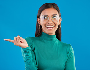 Image showing Mockup, Indian woman and pointing with space, smile and advertising with girl against a blue studio background. Female, lady and gesture for direction, happiness and branding development with smile