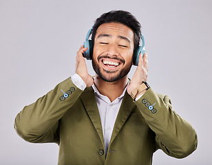 Image showing Music, headphones and business man singing in studio isolated on a gray background. Ceo, entrepreneur and smile of happy male singer streaming, listening and enjoying podcast, radio and song album.