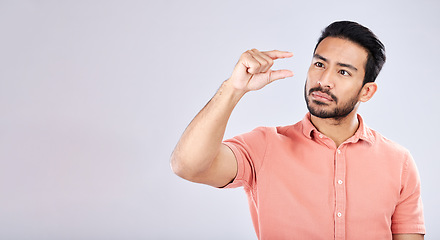 Image showing Hand gesture, size and mockup with a man in studio on a gray background to measure product placement space. Tiny, small and scale with a handsome young male sizing or measuring mock up on a wall