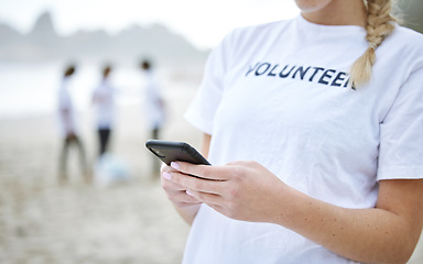 Image showing Phone, hands and volunteer woman at beach for cleaning, social media and web browsing. Earth day, environmental sustainability and female with 5g mobile smartphone at seashore for community service.