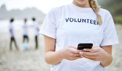 Image showing Hands, phone and volunteer woman at beach for cleaning, social media and web browsing. Earth day, environmental sustainability and female with 5g mobile smartphone at seashore for community service.