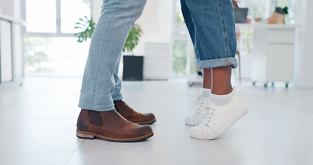 Image showing Closeup, shoes and couple in tiptoe moment, romance and sweet relationship in their home. Feet, love and man with woman embracing, leaning and sharing intimate, embrace and romantic in living room