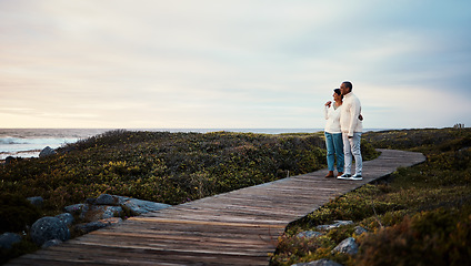 Image showing Love, travel and elderly couple hug on a boardwalk at a beach, calm and content against blue sky background. Senior, man with woman on ocean trip, holiday or vacation, happy and enjoying retirement