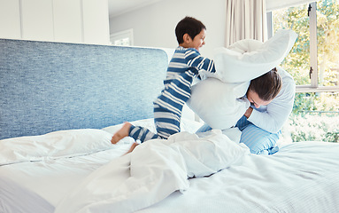 Image showing Playing, dad and son in pillow fight on bed, fun quality time and man bonding with child at home. Smile, happy and play, father and kid in bedroom with pillows, joy and happiness together on weekend.