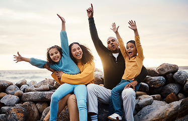 Image showing Black family, parents and kids in beach portrait with hands in air, sitting and rocks with celebration. Black woman, man and children by ocean with love hug, care and bonding on holiday by sunset sky