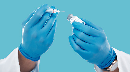 Image showing Closeup, hands and needle for vaccine, healthcare and research with blue studio background. Zoom, gloves and liquid bottle with medical equipment, medicine and vial for cure, vaccination and results